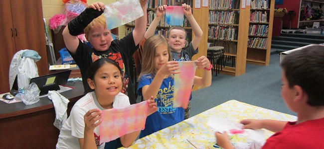 gr ss holding up pictures in library